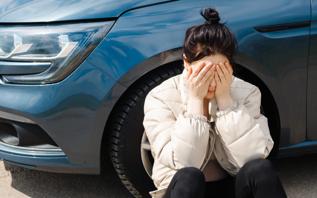 A tired girl, with a broke car wait for an emergency in difficult traffic,